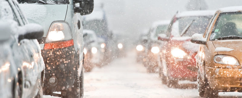 Front view of traffic with cars in a snowy road