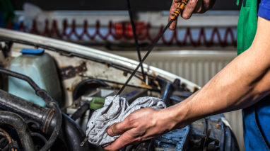 Open car hood with someone cheking the oil