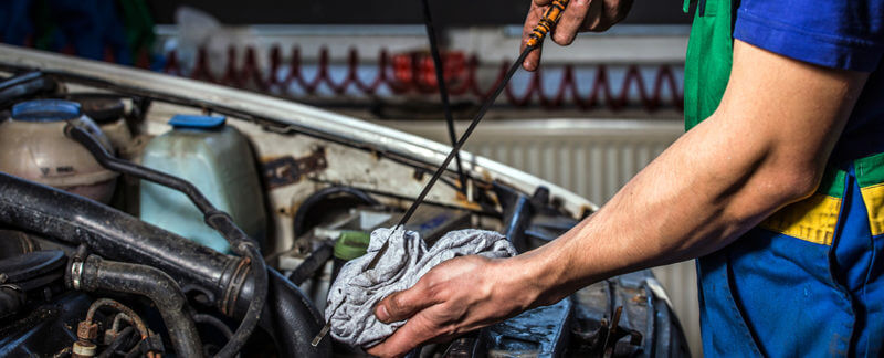 Open car hood with someone cheking the oil