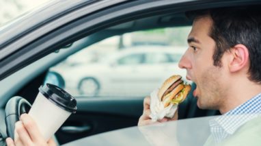 Man driving while eating and driking coffee