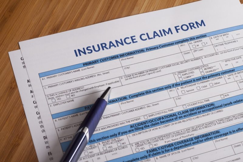 Paper insurance claim form with a pen