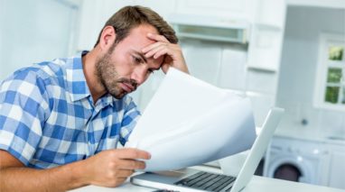 Worried man looking at a document in front of a laptop