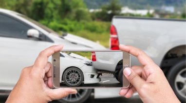 Hands taking a picture of a car accident with a smartphone