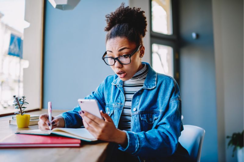 Woman looking for car insurance on her phone and taking notes