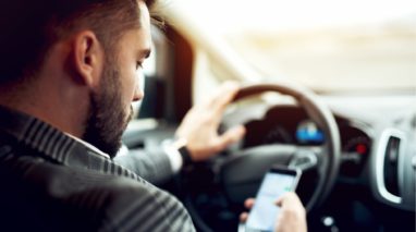 Man driving and looking at his smarthphone