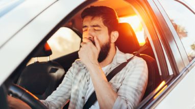 Man driving and yawning while driving tired