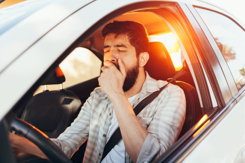 Man driving and yawning while driving tired