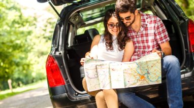 Happy couple looking at a map in the back of their car