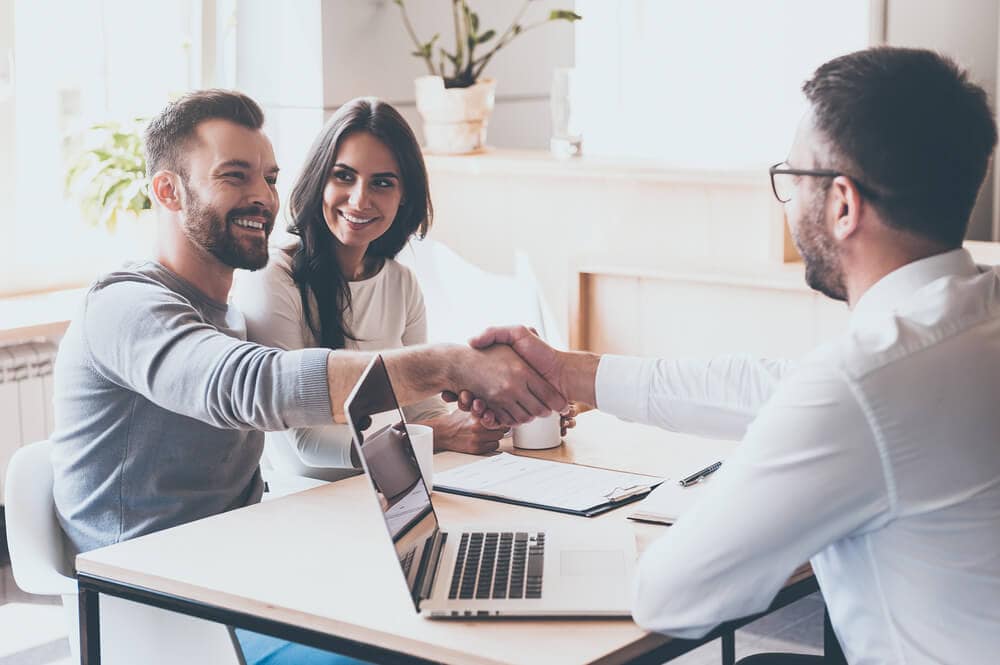 happy couple with insurance agent shaking hands