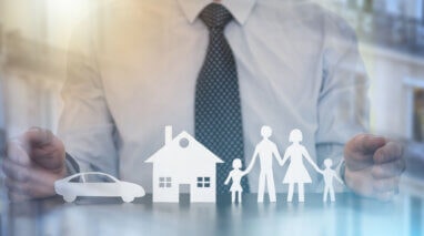 Insurer protecting a family, a house and a car with his hands