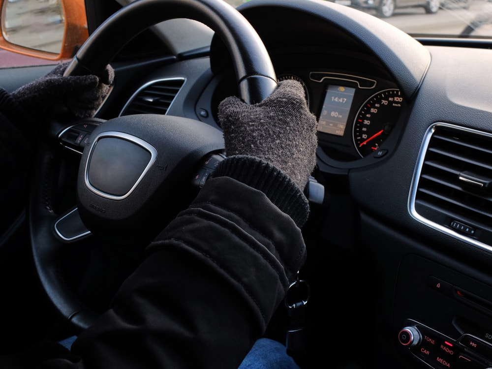 person with gloves on gripping steering wheel