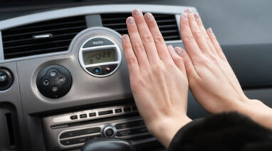 woman warming hands in car in front of vents