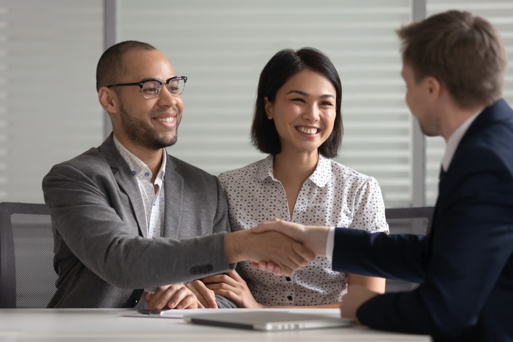 couple shaking hands with insurance agent