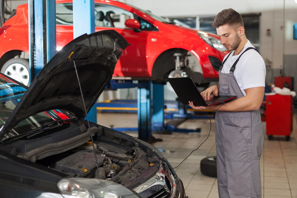 mechanic working on car with hood up in shop