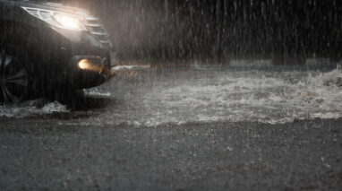 car on road with head lights on driving in heavy rain