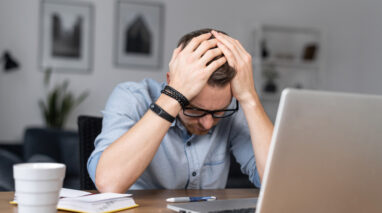 burnt out insurance agent sitting at desk with head in hands