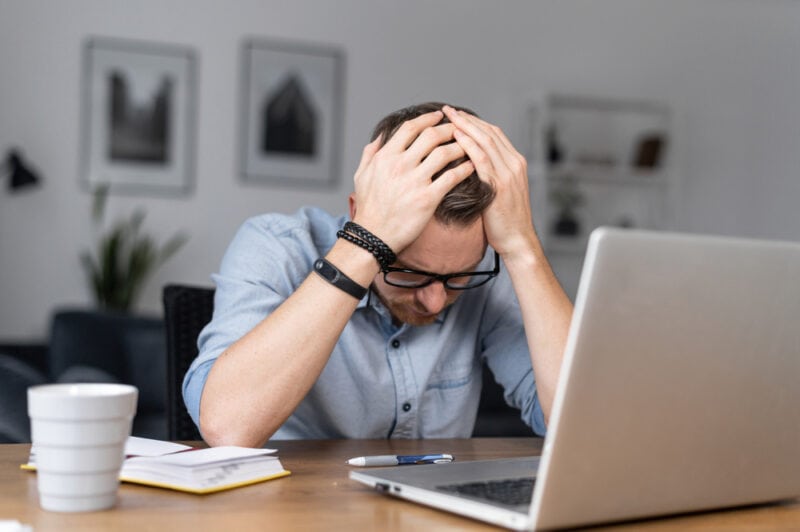 burnt out insurance agent sitting at desk with head in hands