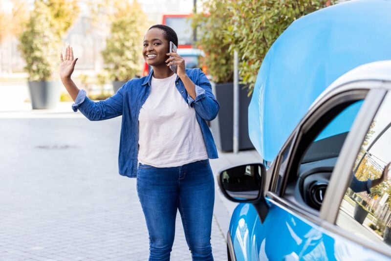 Cheerful African American woman calls roadside assistance