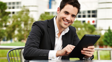 Young businessman works on tablet outside