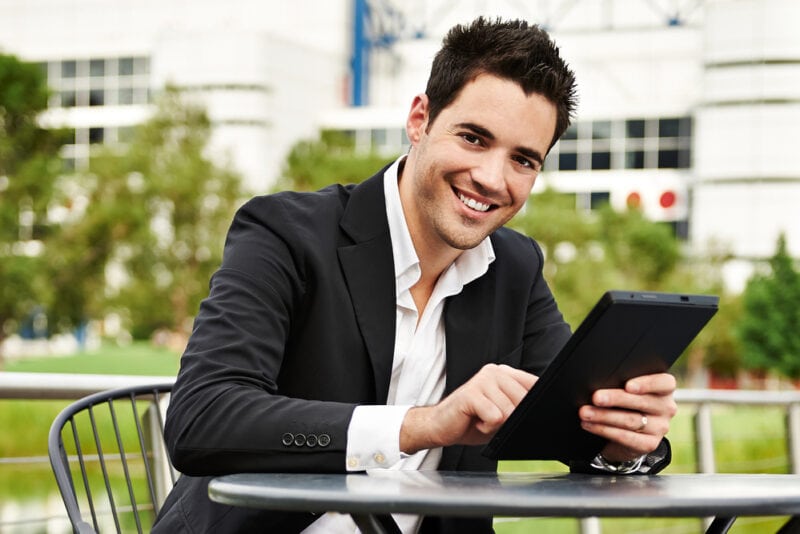 Young businessman works on tablet outside