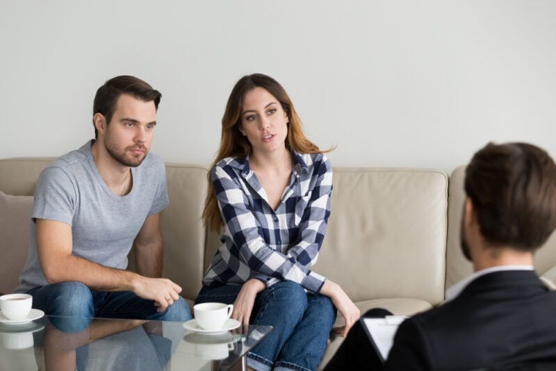 Stressed millennial couple talking to insurance agent about high prices - independent insurance agent car insurance