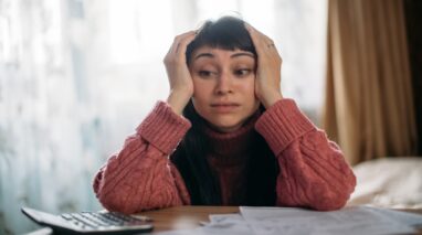 Sad woman holding her head with insurance bill on table