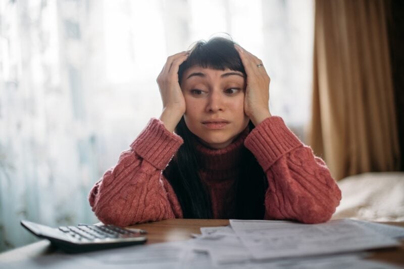 Sad woman holding her head with insurance bill on table